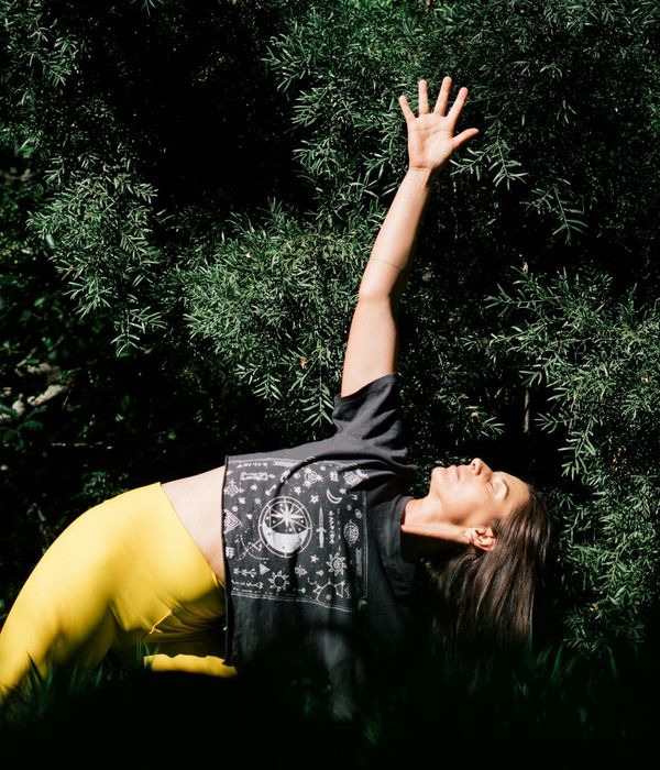 Woman in a calm yoga pose in a dark room with warm lighting.